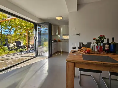 a kitchen and dining room with a table with wine glasses at Casa Miranda - family comfort in a quiet area, near the sea, with BBQ and FREE parking in Zgornje Škofije