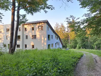 a white building in the middle of a forest at Apartment Alpina in Pohorje