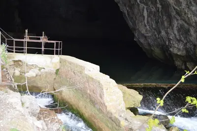 a river in a cave with a fence on the side at Apartma Nika in Planina