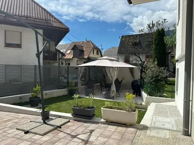 a patio with an umbrella and chairs and a yard at APARTMA ALMA in Bovec