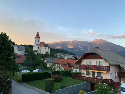 a village with a church and mountains in the background at La casa verde in Bled-Rečica