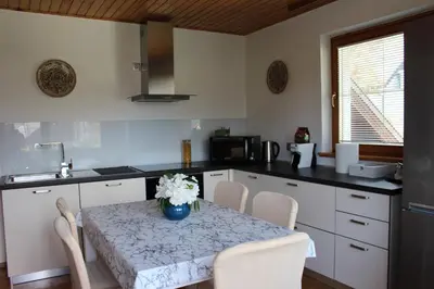a kitchen with a table with white chairs and a sink at La casa verde in Bled-Rečica