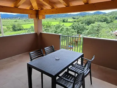 a black table and chairs on a balcony with a view at Posestvo Rouna - winery and apartments in Vipava