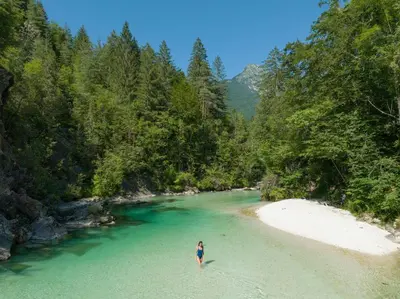 a person standing on a beach in the middle of a river at Cabino - Fresh Air Resort in Bovec