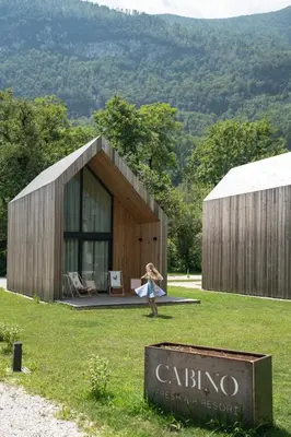 a woman walking in front of a small building at Cabino - Fresh Air Resort in Bovec