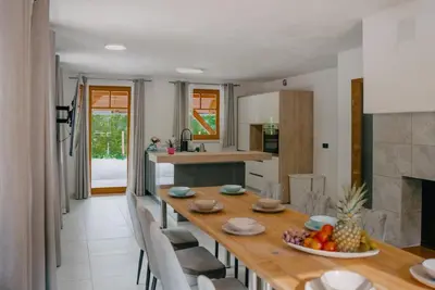 a kitchen and dining room with a wooden table and chairs at Chalet HerMes arT in Idrija