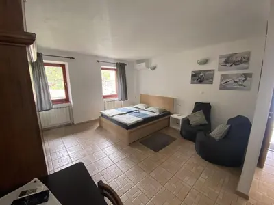 a bedroom with a bed and a couch and a chair at Apartmaji SOČA in Most na Soči