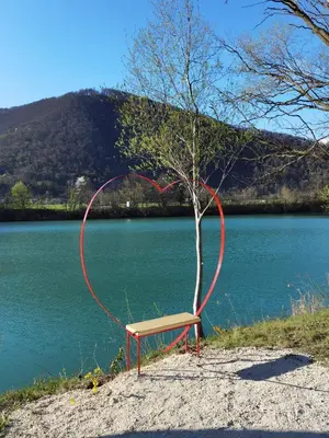 a bench sitting next to a tree next to a river at Apartmaji SOČA in Most na Soči