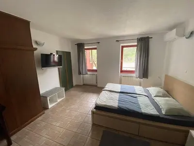 a bedroom with a bed and a tv and two windows at Apartmaji SOČA in Most na Soči