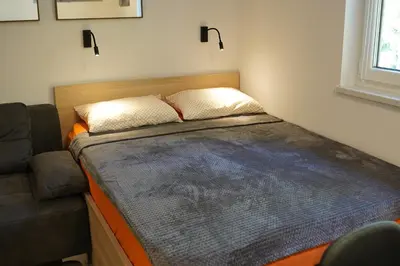 a small bed in a room with a couch at Studio Pika in Kranjska Gora