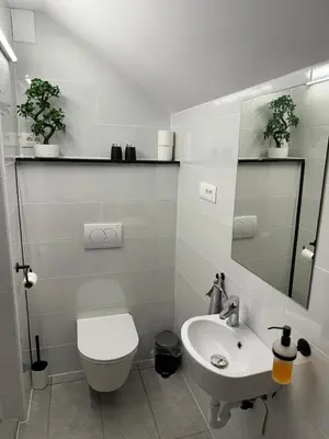 a white bathroom with a toilet and a sink at Green Oasis Garden in Šenčur
