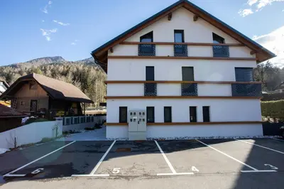 a large white building with a parking lot at Studio Vilawin Kranjska Gora in Kranjska Gora