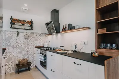 a kitchen with white cabinets and a black counter top at Janina's Dragonfly house in Nova Vas