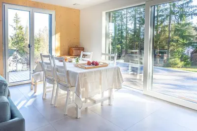a dining room with a table and chairs and windows at Janina's Dragonfly house in Nova Vas