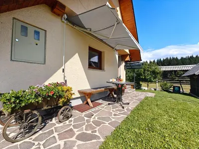 a patio with a picnic table and awning on a house at Cottage Zoja in Bohinjska Bistrica