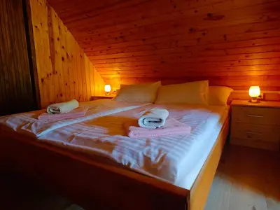 a bed in a wooden room with towels on it at Cottage Zoja in Bohinjska Bistrica