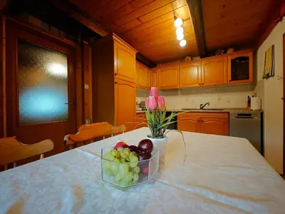 a kitchen with a bowl of fruit and flowers on a counter at Cottage Zoja in Bohinjska Bistrica