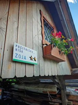 a sign on the side of a building with flowers in a window at Cottage Zoja in Bohinjska Bistrica