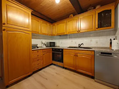 a kitchen with wooden cabinets and stainless steel appliances at Cottage Zoja in Bohinjska Bistrica
