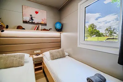 two beds in a small room with a window at DELUXE Lake View Mobile Homes with Thermal Riviera Tickets in Čatež ob Savi