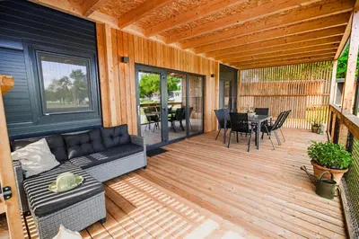 a patio with a couch and a table on a deck at DELUXE Lake View Mobile Homes with Thermal Riviera Tickets in Čatež ob Savi