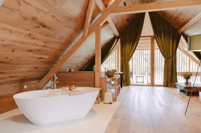 a bathroom with a large tub in a room with wooden ceilings at PIRA HOTEL in Postojna
