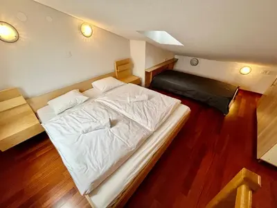 a large white bed in a room with wood floors at Apartment Anka in Bovec