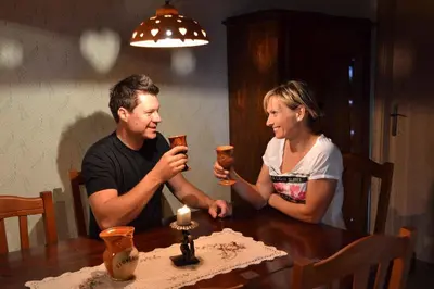 a man and woman sitting at a table with drinks at Holiday home in Srednje Grcevje - Kranjska Krain 26095 in Srednje Grčevje