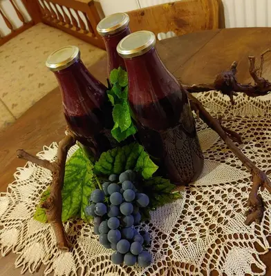 two bottles of wine sitting on a table with grapes at POČITNIŠKA HIŠA PRLEČKA in Miklavž pri Ormožu