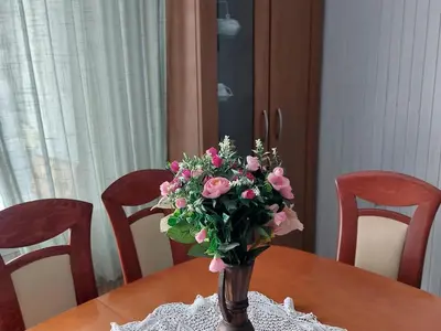 a vase filled with pink roses sitting on a table at Domačija pri Ivankovih in Osilnica