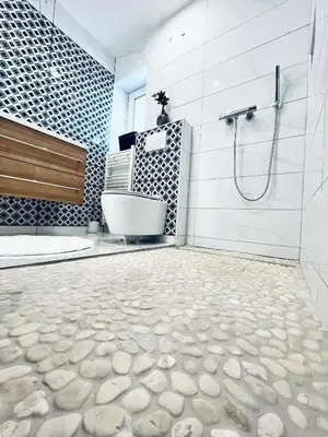 a bathroom with a tub and a shower with rocks on the floor at Luxe Apartments in Ljutomer