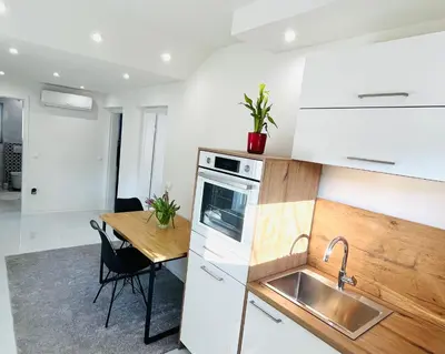 a kitchen with a sink and a wooden table at Luxe Apartments in Ljutomer