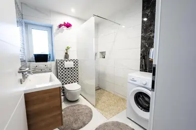 a white bathroom with a washing machine and a washer at Luxe Apartments in Ljutomer