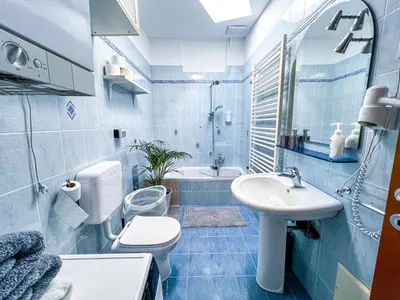 a blue tiled bathroom with a sink and a toilet at Marta's Place in Nova Gorica