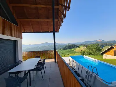 a balcony with a table and chairs and a swimming pool at Villa Strtenica in the vineyard in Pristava pri Mestinju