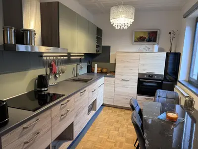 a kitchen with wooden cabinets and a table with chairs at Apartments & wellness Kal Koritnica in Bovec