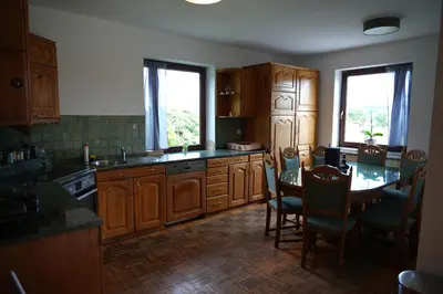 a kitchen with wooden cabinets and a table with chairs at Rooms and apartments Biš in Trnovska Vas