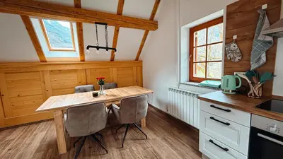 a kitchen with a wooden table and two chairs at Apartments Mala Korita Soče in Soča