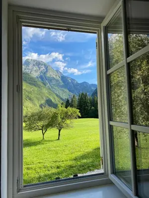 a window with a view of a field and mountains at Apartments Mala Korita Soče in Soča