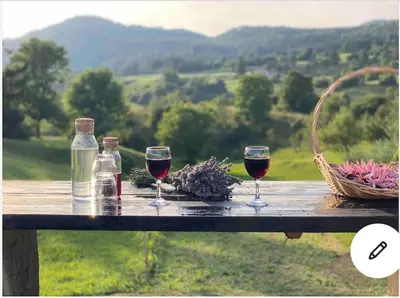 two glasses of wine and a basket of flowers on a wooden table at Spacious apartment in nature with sauna! in Postojna
