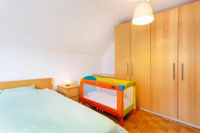 a bedroom with a bed and a childs chair at Farmhouse Apartment Happy Cow in Mavčiče