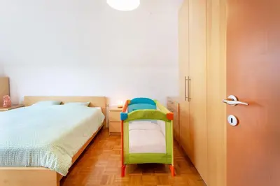 a bedroom with a green chair next to a bed at Farmhouse Apartment Happy Cow in Mavčiče