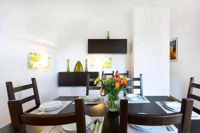 a dining room with a table with a vase of flowers at Farmhouse Apartment Happy Cow in Mavčiče