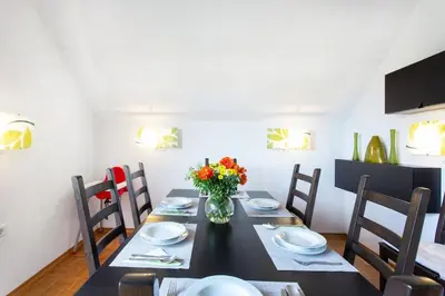 a dining room with a table with chairs and a vase of flowers at Farmhouse Apartment Happy Cow in Mavčiče