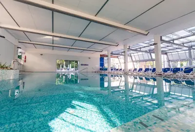 a swimming pool with blue chairs in a building at Hotel Švicarija - Terme Dobrna in Dobrna