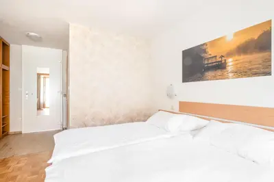 a bedroom with a white bed and a painting on the wall at Terme Banovci - Hotelsko naselje Zeleni gaj in Banovci