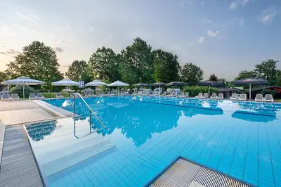a large blue swimming pool with chairs and umbrellas at Terme Banovci - Hotelsko naselje Zeleni gaj in Banovci