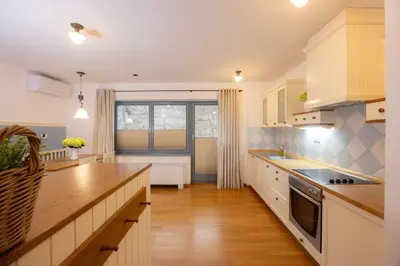 a kitchen with white cabinets and a large window at Lakeside Apartments Bled in Bled