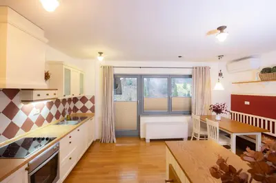 a kitchen with white cabinets and a table and a dining room at Lakeside Apartments Bled in Bled