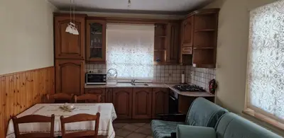 a kitchen with wooden cabinets and a table with a white table cloth at Apartma Arkade in Črniče